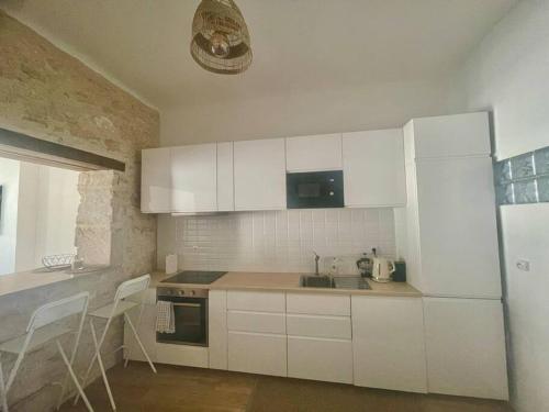 La cuisine blanche est équipée d'un évier et d'un réfrigérateur. dans l'établissement Charmant 2 pièces à Joliette, à Marseille