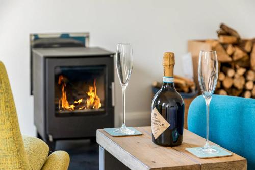 a bottle of wine and two glasses on a table with a fireplace at The Bamboo Lodge - B&B / self-catered apartment in Ashford