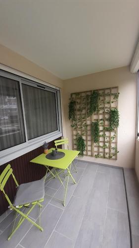 Habitación con mesa verde, sillas y ventana en Joli Appartement T2 avec Balcon "Le nid Libaud" en Chalon-sur-Saône