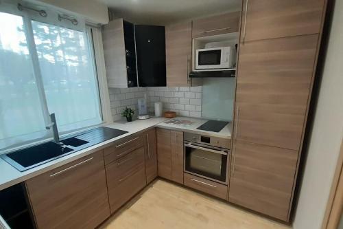 kuchnia z drewnianymi szafkami, umywalką i oknem w obiekcie Joli Appartement T2 avec Balcon "Le nid Libaud" w mieście Chalon-sur-Saône
