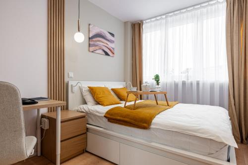 a bedroom with a bed with a desk and a window at 9th Floor Wroclaw Business Apartment by Rentujemy in Wrocław