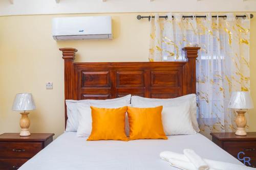 a bedroom with a bed with orange and white pillows at Charming refuge at Colbeck Manor in Old Harbour