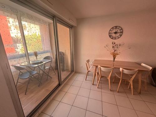 a dining room with a table and chairs and a clock at Classé 3 Etoiles Charmant Appartement Cosy sur Sète proche de toutes commodités, Parking Privé in Sète