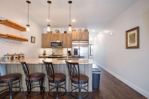 a kitchen with a bar with four stools at River West Buffalo Mountain Condo: On The Blue River in Silverthorne