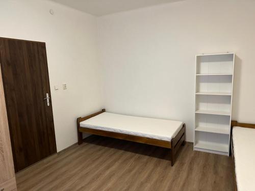 een kleine kamer met een bed en een boekenplank bij Breznicka 91 in Příbram