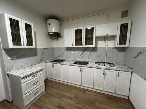 una cocina con armarios blancos y encimeras de mármol en Breznicka 91 en Příbram