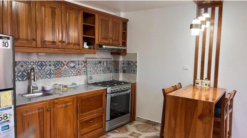 uma cozinha com armários de madeira e um forno com placa de fogão em Kimsa Wasi III em Otavalo
