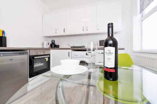 Una botella de vino sentada en una mesa de cristal en una cocina en The Urban Apartment, en Doncaster