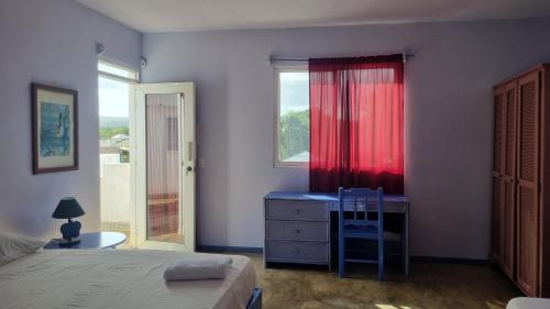 a bedroom with a bed and a dresser with a red curtain at Il Triangolo Hostel in Las Galeras