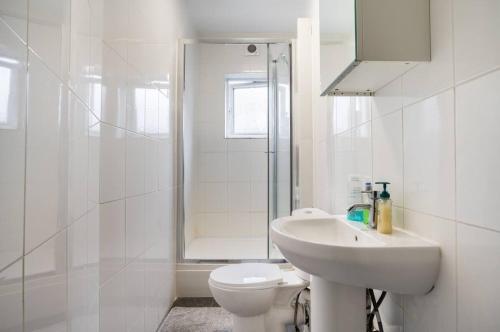 a white bathroom with a sink and a toilet at Hatton Homes - Thackeray Avenue in London