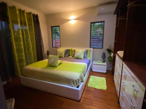 a bedroom with a bed with green sheets and windows at Villa Ora Na in Mahina