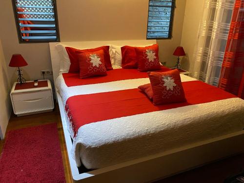 a bedroom with a large bed with red pillows at Villa Ora Na in Mahina