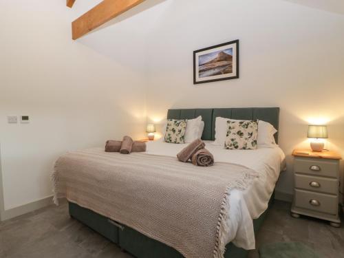 a bedroom with a large bed with two lamps at The Byre in Bridgend