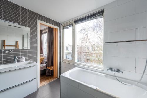 a bathroom with a white tub and a window at Bed zonder Breakfast in Amsterdam