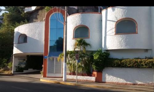 a white building with a large door on a street at Hotel Oasis Acapulco in Acapulco