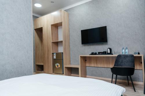 1 dormitorio con 1 cama y escritorio con TV en Sunrise Hotel, en Taldykorgan