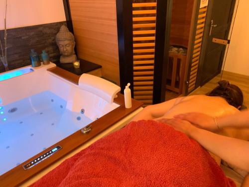 uma pessoa deitada na cama em frente a uma banheira em L’atelier spa em Codognan