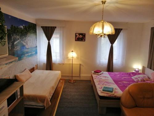 Habitación pequeña con 2 camas y lámpara de araña. en Penzion JURA, en Chřibská