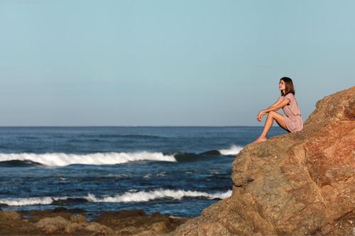 a woman sitting on a rock by the ocean at JW Marriott Guanacaste Resort & Spa in Tamarindo