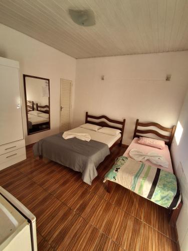 two beds in a room with wood flooring at Hotel Nuar in Betim