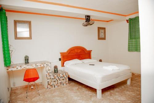 um quarto com uma cama branca e uma cadeira vermelha em MOONLIGHT HOTEL BAR RESTO em Hinche