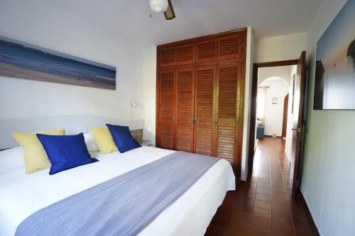 sypialnia z dużym łóżkiem z niebieskimi i żółtymi poduszkami w obiekcie APARTAMENTO SON BOU w Son Bou