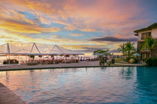 a swimming pool with a view of the ocean at sunset at JW Marriott Guanacaste Resort & Spa in Tamarindo