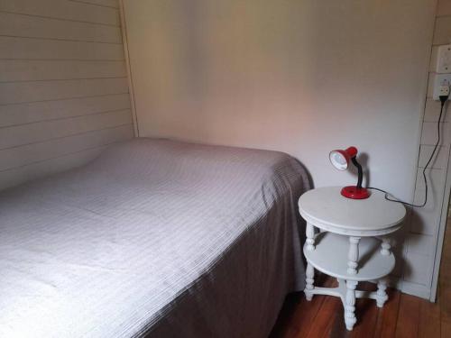 um quarto com uma cama e uma pequena mesa com um candeeiro em Casa da Montanha: Minha Casa, tua Casa! em Gravatal