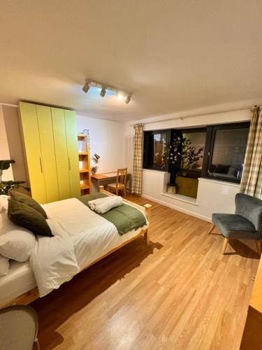 een slaapkamer met een bed, een stoel en ramen bij Luxury 2 BHK in Canary Wharf in Londen