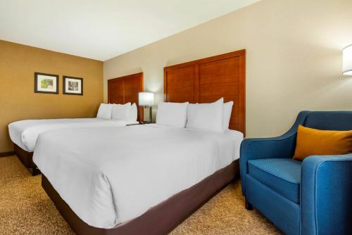 a hotel room with two beds and a blue chair at Comfort Inn Parry Sound in Parry Sound