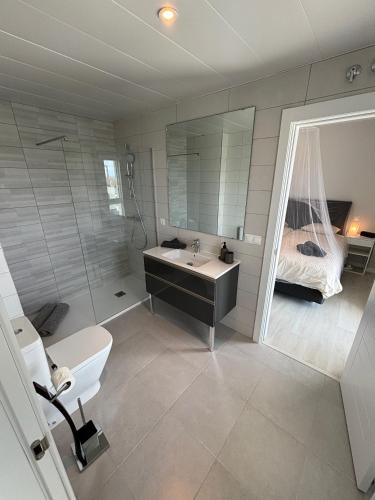 a bathroom with a sink and a toilet and a bed at New penthouse with sunny beach view in Huelva
