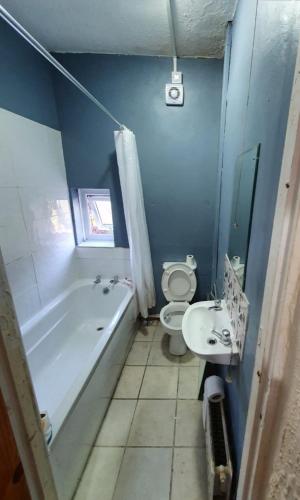 a bathroom with a tub and a toilet and a sink at Adams House in Manchester