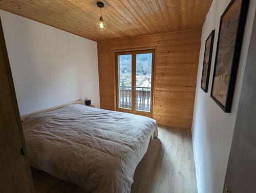une chambre avec un lit dans une pièce avec une fenêtre dans l'établissement Appartement rénové proche centre ville navette 6-8 personnes multipass, à Châtel