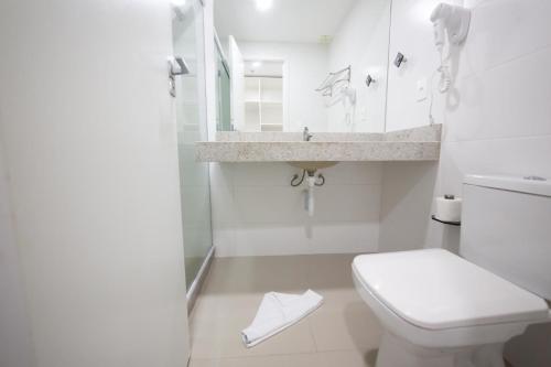 um banheiro branco com um vaso sanitário e uma pia em Flat 428 no centro de Cabo Frio a 700m da praia em Cabo Frio