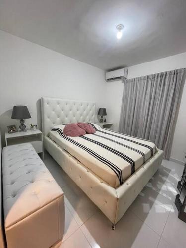 a bedroom with a bed and a bench in it at Hermoso apartamento con piscina. in La Estrella