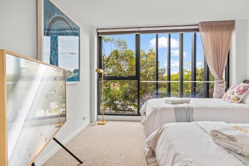 a bedroom with two beds and a large window at StayAU Modern 2BR Townhouse w/ pool in Oakleigh
