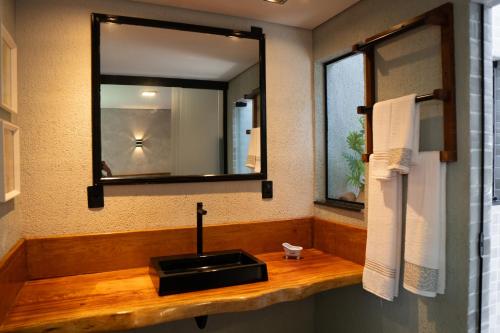 uma casa de banho com um lavatório preto e um espelho em Pousada Novo Prado em Prado
