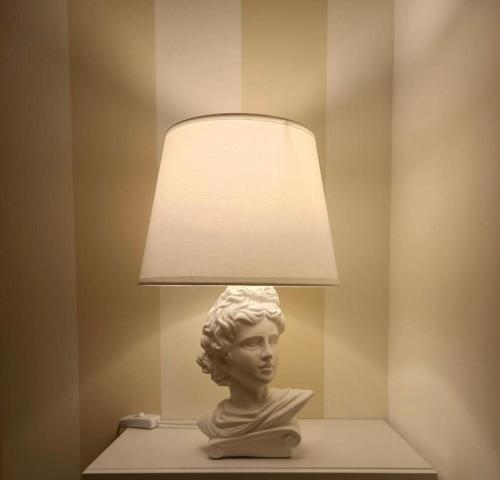 una estatua de un busto sentada en una mesa con una lámpara en Le Stanze del Castello, en Ascoli Satriano