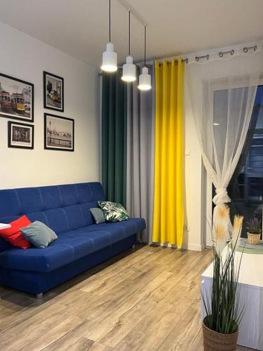 - un salon avec un canapé bleu et des rideaux jaunes dans l'établissement Apartament Chiara, à Oleśnica