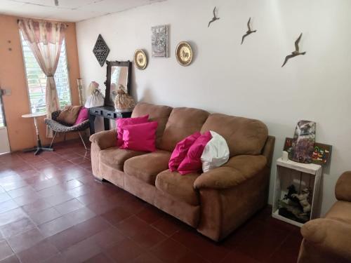 uma sala de estar com um sofá castanho com almofadas cor-de-rosa em Santa Tecla Acogedora Guest House em Nueva San Salvador