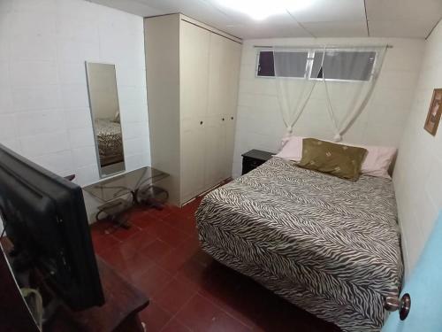 Dormitorio pequeño con cama y TV en Santa Tecla Acogedora Guest House, en Nueva San Salvador