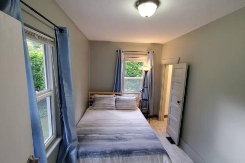 una piccola camera da letto con un letto e due finestre di Cozy Cottages across from the Food Trucks of Aloha mall ad Aloha