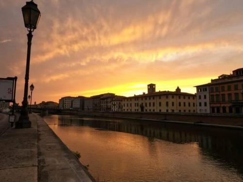 a sunset over a river with buildings and a street light at Romantic Suite in Pisa
