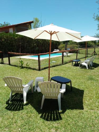 a table and chairs and an umbrella next to a pool at INTI MAYU Cabañas in Mina Clavero