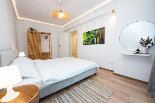 Habitación blanca con cama y espejo en EGO Apartment en Târgu Mureș