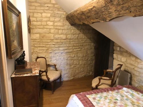 1 dormitorio con cama, sillas y pared de piedra en Manoir de Pimelles-Bourgogne-Chablis-2h15 Paris, 