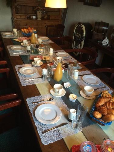 una larga mesa de madera con platos de comida. en Le Petit Moulin, en Saint-Hilaire