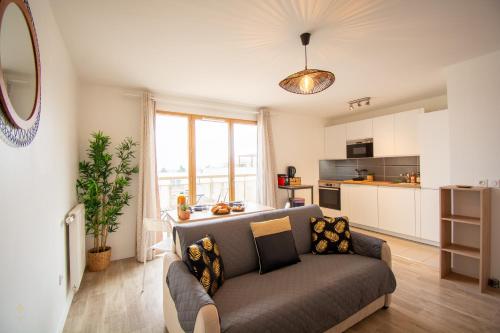 uma sala de estar com um sofá e uma cozinha em 2 pièces Vitry rénové avec balcon (15 min Paris) em Vitry-sur-Seine