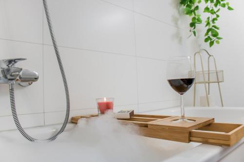 una copa de vino sentada en una bandeja de madera en la bañera en Moonshine Apartment - Altstadtflair in der City mit Parkplatz und Home Office en Brunswick