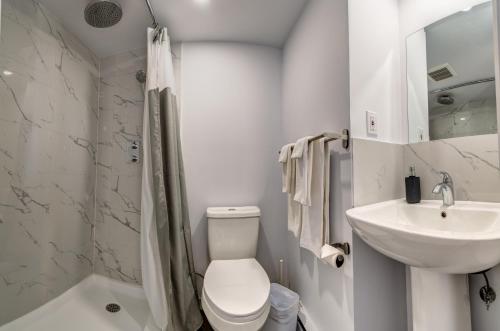 Baño blanco con aseo y lavamanos en Motel Saint Bruno, en Saint-Bruno-de-Montarville